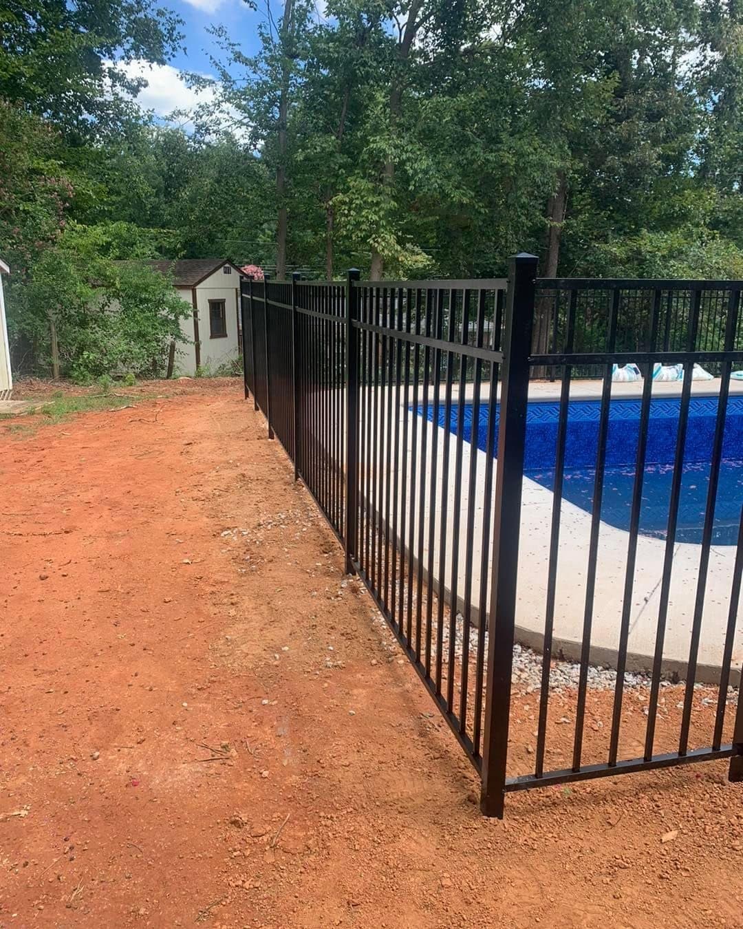 Black aluminum pool safety fence surrounding a backyard swimming pool by Advanced Custom Fence in Charlotte, NC